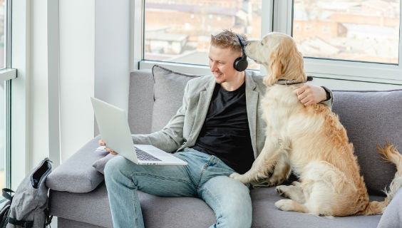 Mand sidder i sofa med laptop og høretelefoner